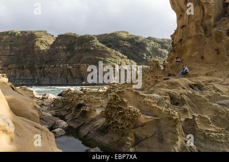 La gente seduta a una scogliera a bizzarre del terreno e le formazioni rocciose a Heping (spero) Island Park, Keelung, Taiwan Foto Stock