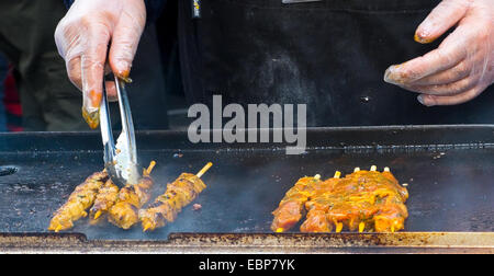 Gli spiedini di carne la cottura su una griglia in un mercato. Cucina di strada. Foto Stock