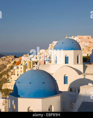 Ia, Santorini, Egeo Meridionale, Grecia. Tipico blu-chiese a cupola illuminata dal sole nascente. Foto Stock