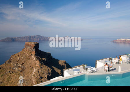 Imerovigli, Santorini, Egeo Meridionale, Grecia. Vista di Skaros Rock e l'isola di Thirasia, i turisti a colazione accanto alla piscina. Foto Stock