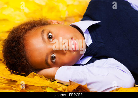 Little Black boy stabilisce in autunno foglie di acero Foto Stock