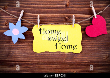 Giallo cartellino o etichetta con il cuore e con fiore su una linea con la vita Preventivo Home Sweet Home su sfondo di legno, due simboli, vintage, Foto Stock