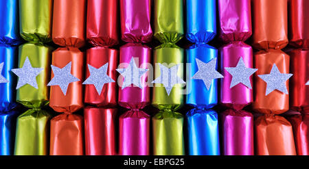 Fila di shiny festive Christmas Cracker bon bons in brillante Allegro rosso, rosa, arancione, colori blu e verde. Foto Stock