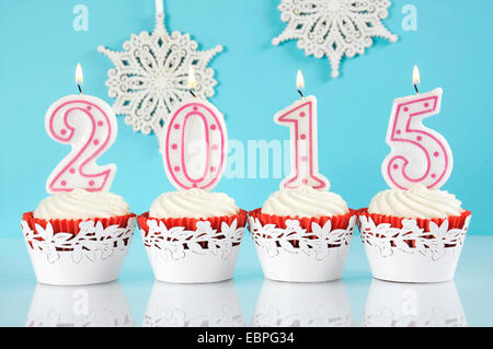 Felice anno nuovo per il 2015 Red Velvet tortine in rosso e bianco tema con candele accese e decorazioni a fiocco di neve Foto Stock