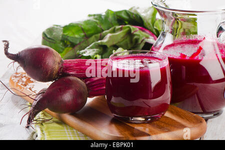 Succo di barbabietola e il mazzetto di barbabietole fresche con foglie. Messa a fuoco selettiva Foto Stock