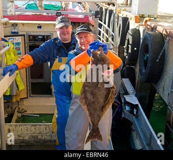 Due pescatori con catturato ippoglosso di Nizza sulla pesca a strascico, Norvegia, Isole Lofoten Foto Stock