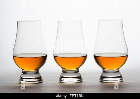 Tre retro-illuminato bicchieri in cristallo ambra contenenti liquore. Whiskey bourbon, il brandy, ecc. Foto Stock