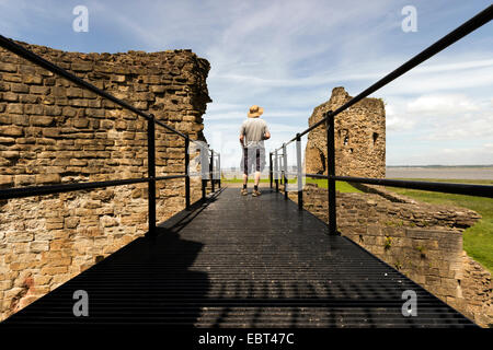 Uomo in piedi su un ponte e il castello del XIII secolo ruderi, Flint Castle, Galles del Nord, Regno Unito Foto Stock