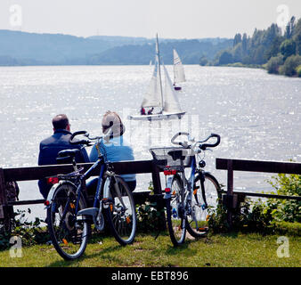 Giovane con le bici seduta su una panchina a guardare al Lago Kemande, Kemnader vedere, in Germania, in Renania settentrionale-Vestfalia, la zona della Ruhr, Bochum Foto Stock