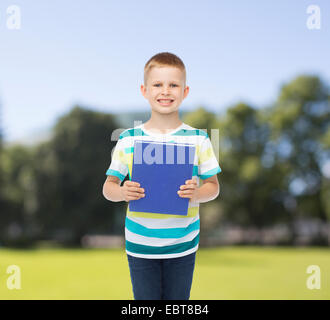 Poco sorridente studente Ragazzo con libro blu Foto Stock