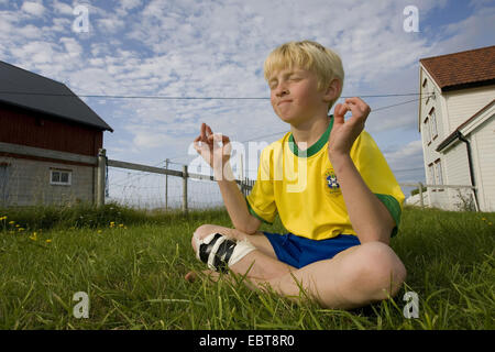 Giovane ragazzo giocando nella posizione del loto, Norvegia Foto Stock