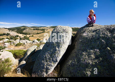 Bambino accovacciato su roccia, Francia, CÚvennes Foto Stock