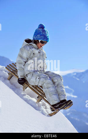 Ragazzo in slittino sulla neve, Francia Foto Stock