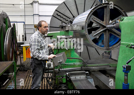 Lavoratore anziano nell'industria del metallo in corrispondenza di una macchina CNC Foto Stock