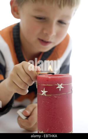 Little Boy accendere una candela con un matchstick Foto Stock