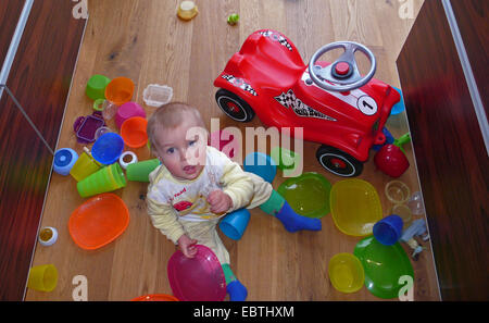 Bambino seduto per terra e giocare con i piatti di plastica Foto Stock