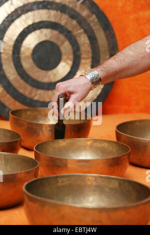 Uno dei vari SINGING BOWLS in piedi sul suolo è colpito da un battaglio Foto Stock