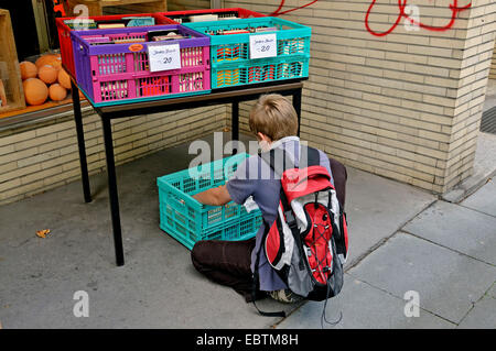 Ragazzo cerca offerte speciali nella parte anteriore di una seconda mano bookshop, in Germania, in Renania settentrionale-Vestfalia, Wuppertal Foto Stock