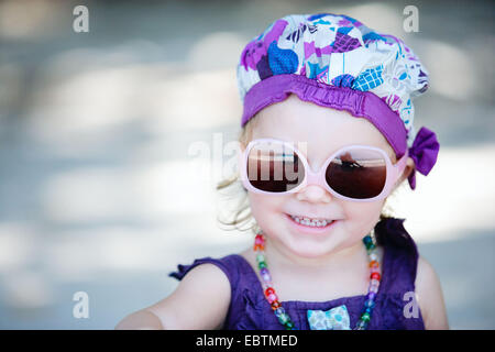 Ritratto di una bambina che indossa gli occhiali da sole e vestiti di fantasia Foto Stock