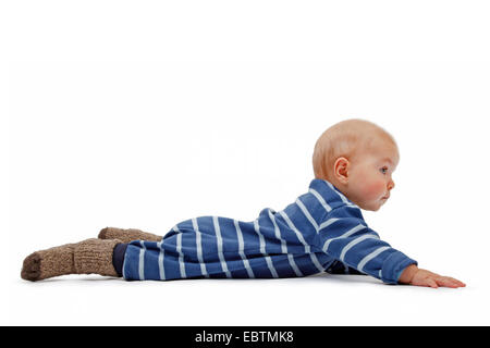 Little Boy indossando romper striped suit giacente a terra e sollevamento testata Foto Stock