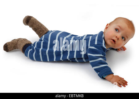 Little Boy indossando romper striped suit giacente a terra e ruotare la testa Foto Stock