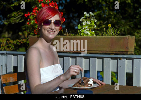 Giovane donna redhaired mangiando un pezzo di torta, Germania Foto Stock