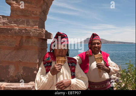 Due indiani in abiti tradizionali giocando panflutes presso la riva del lago Titicaca, Perù, Taquile Island, il lago Titicaca Foto Stock
