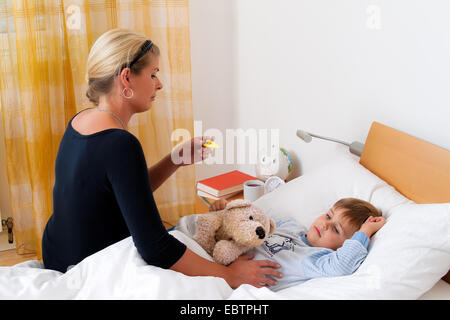 Madre seduta al posto letto del suo bambino malato Foto Stock