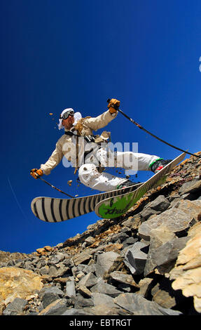 Sciatore freeride dissimulata come oldfashioned avventuriero in discesa sul pendio roccioso Foto Stock