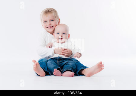 Piccolo Ragazzo seduto sul pavimento con la sua sorellina nel giro Foto Stock