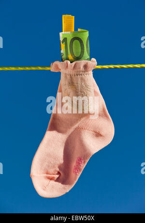 Baby calza con banconote in euro su stendibiancheria Foto Stock