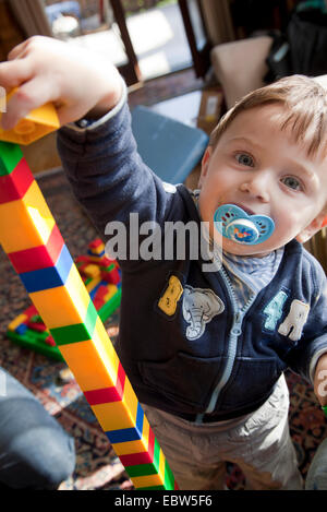 Little Boy la costruzione di una torre di LEGO che è di molto superiore a quella che egli è Foto Stock