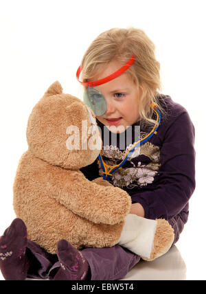 Bambino con uno stetoscopio come un medico, esamina teddy Foto Stock