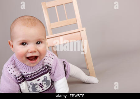 Bambina sul terreno di fronte a un seggiolino per bambino Foto Stock