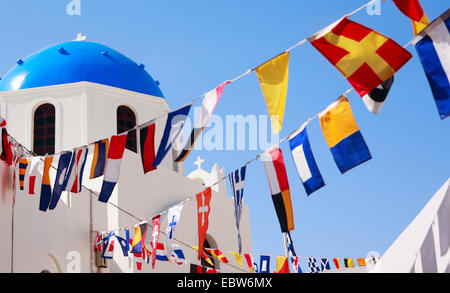 Blue greco chiesa a cupola e colorata flaggs, Grecia SANTORINI, CICLADI, Oia Foto Stock