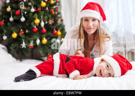 Giovane madre giocando con il bambino vestito in costume di Santa Foto Stock