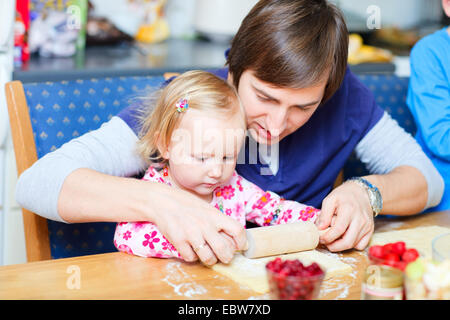 Padre la cottura biscotti con la sua piccola figlia Foto Stock