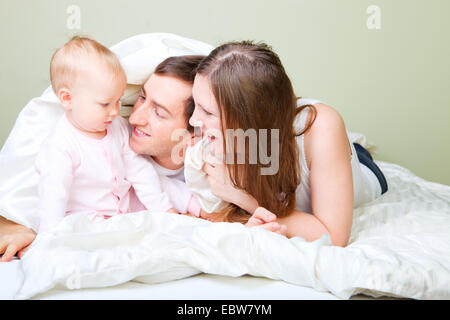 Famiglia giovane giacente in letto con piccola figlia Foto Stock