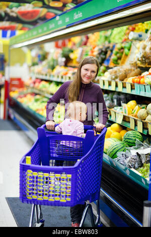 Una giovane madre con bambino acquisti in un supermercato Foto Stock