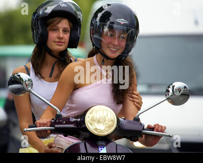 Due giovani attraenti donne equitazione su scooter Foto Stock