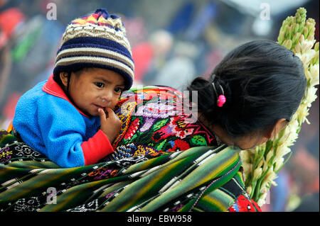 Bambino sulla schiena della madre che sta lavorando in un campo, Guatemala Foto Stock