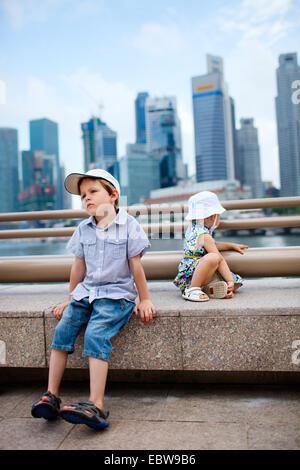 Due piccoli bambini seduti nel centro città, Singapore, Singapore Foto Stock