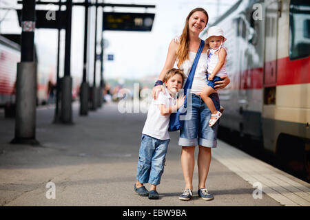 Una giovane madre con i suoi due bambini in attesa del treno Foto Stock