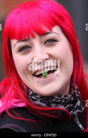 Giovane donna con capelli rosa mangiando caramelle Foto Stock
