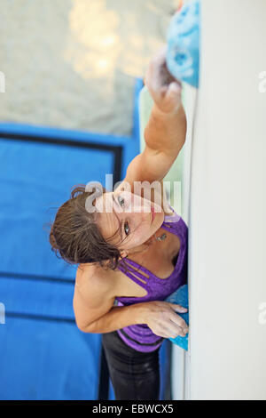 Scalatore femmina su artificiale di arrampicata di raggiungere il prossimo appiglio Foto Stock