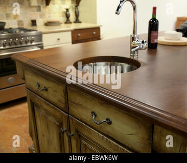 Addolorato mobili da cucina, bancone in legno con moderne in acciaio inox rubinetto e lavandino. Foto Stock