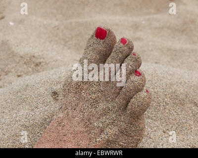 Sabbia-cibo coperto con unghie verniciate sulla spiaggia Foto Stock
