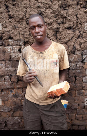 Lavoratore con mattoni di argilla e il bit in piedi di fronte ad una parete, Burundi, Karuzi, Buhiga Foto Stock