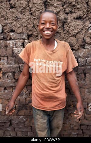 Felice ragazzo in piedi nella parte anteriore della parete di fango, Burundi, Karuzi, Buhiga Foto Stock