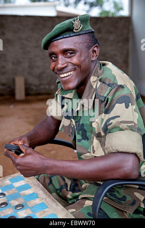 Soldato responsabile per la sicurezza di un campo buero dell ONU è la riproduzione di bozze con un compagno tra i contenitori con il logo dell'organizzazione, Burundi, Makamba, Makamba Foto Stock